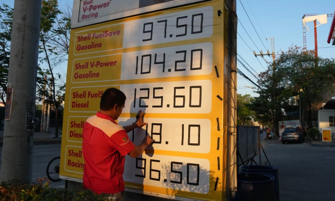 Nhân viên điều chỉnh biển báo giá tại một trạm xăng ở Quezon, Philippines hôm 24/3. Ảnh: AP